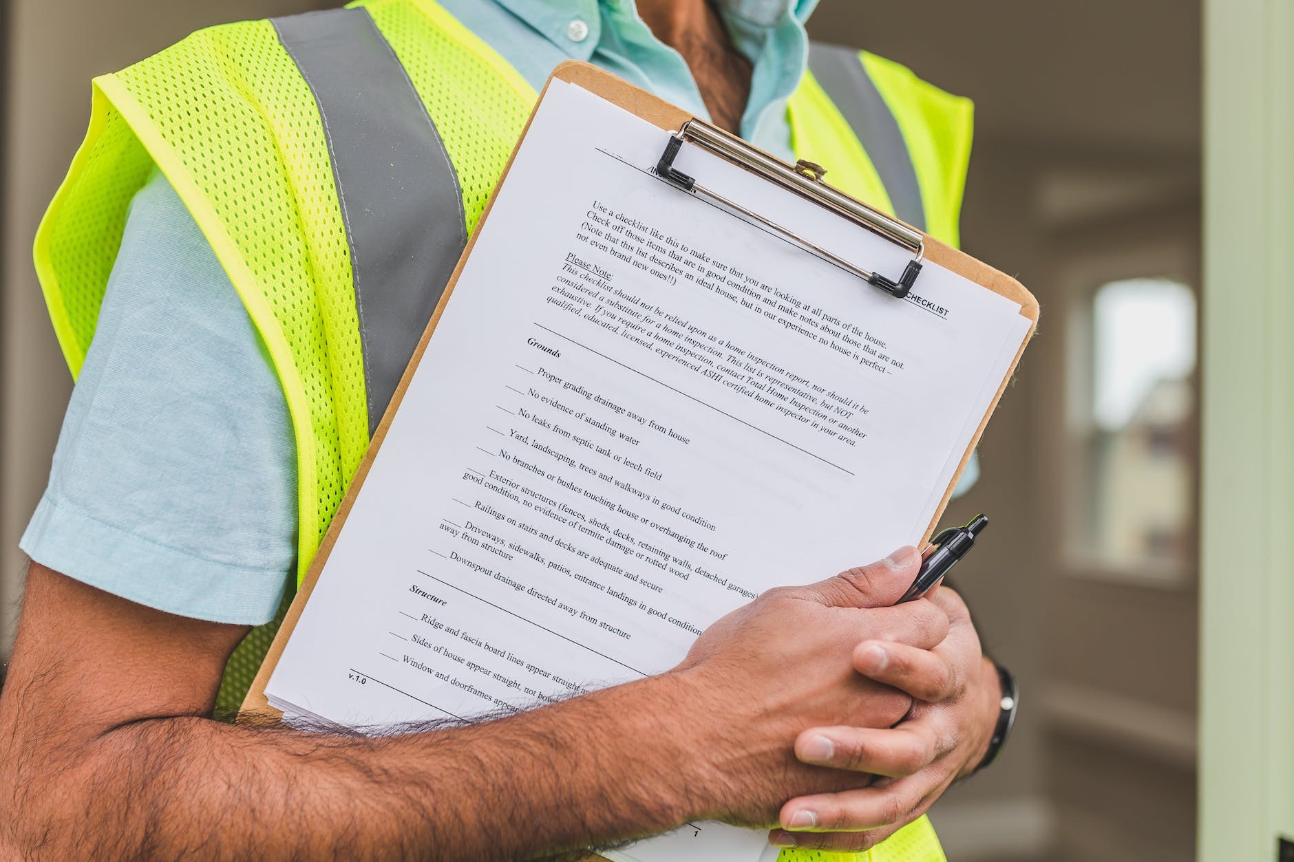 person in yellow reflective safety vest holding a pen and checklist
